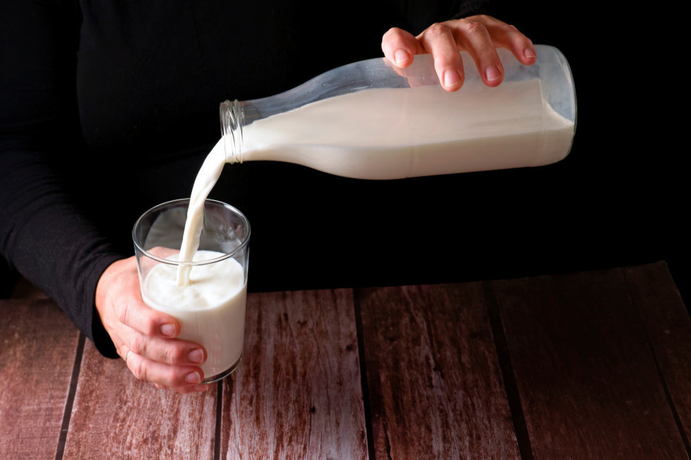 An individual pouring themself a glass of milk